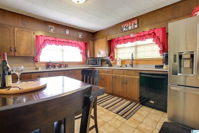 kitchen with sink, wood walls, light tile flooring, and stainless steel appliances