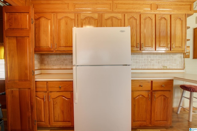 kitchen with backsplash, wood-type flooring, and white fridge