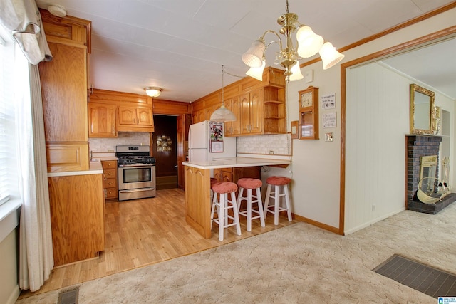 kitchen with backsplash, stainless steel range with gas cooktop, light colored carpet, and white fridge