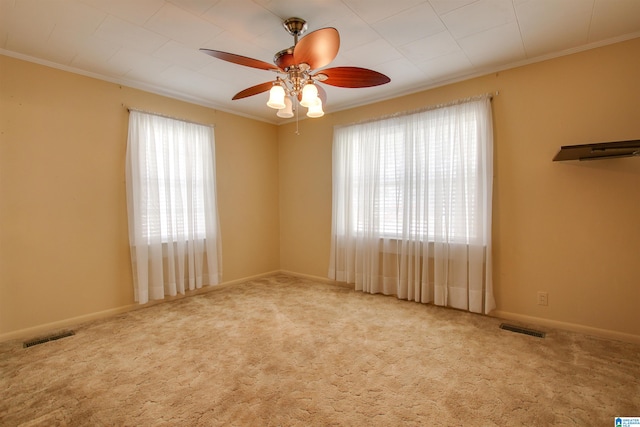 unfurnished room featuring a healthy amount of sunlight, carpet, crown molding, and ceiling fan