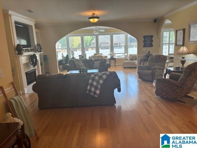 living room with crown molding, wood-type flooring, and ceiling fan