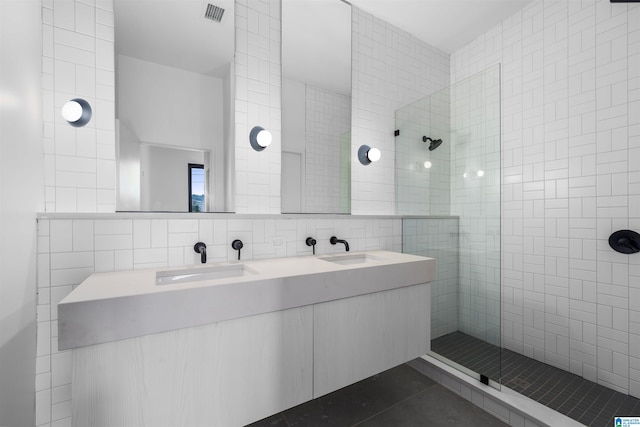 bathroom featuring tile walls, tasteful backsplash, tile patterned floors, tiled shower, and vanity