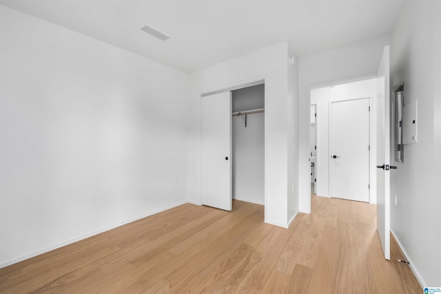 unfurnished bedroom with light wood-type flooring and a closet