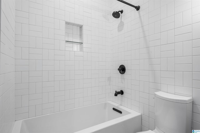 bathroom featuring tiled shower / bath combo and toilet