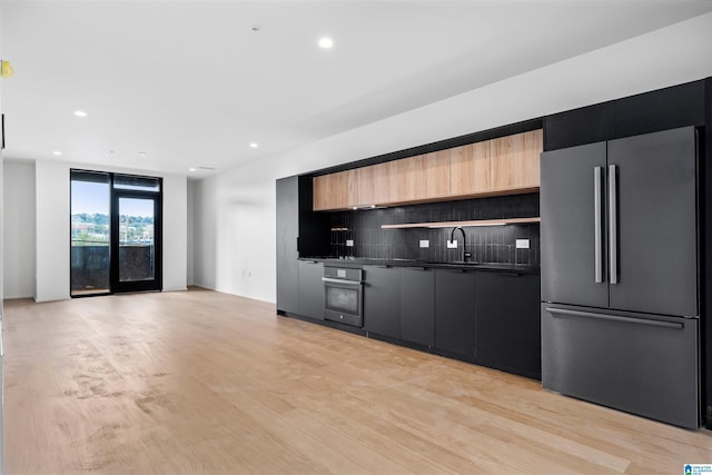 kitchen featuring decorative backsplash, sink, light hardwood / wood-style flooring, and stainless steel appliances