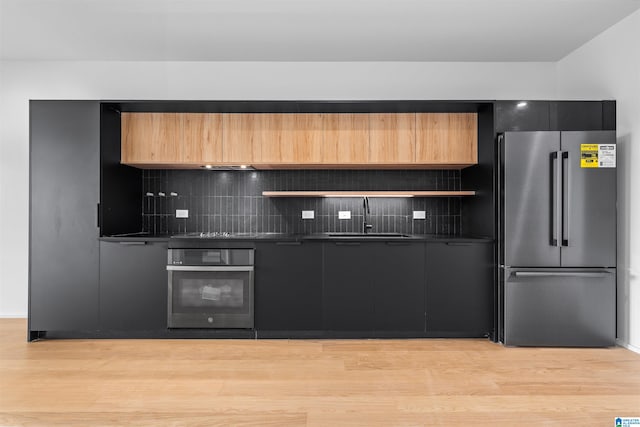 kitchen with light hardwood / wood-style flooring, appliances with stainless steel finishes, tasteful backsplash, and sink