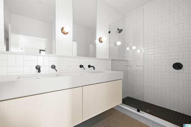 bathroom with vanity, tasteful backsplash, tiled shower, tile patterned floors, and tile walls