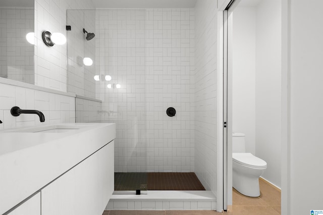 bathroom featuring a tile shower, tile patterned floors, vanity, and toilet