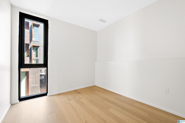 unfurnished room with light wood-type flooring and lofted ceiling