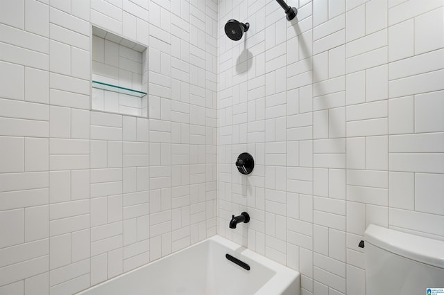 bathroom with tiled shower / bath combo and toilet