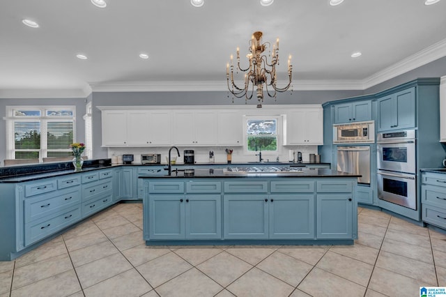 kitchen with crown molding, appliances with stainless steel finishes, a kitchen island with sink, and blue cabinetry