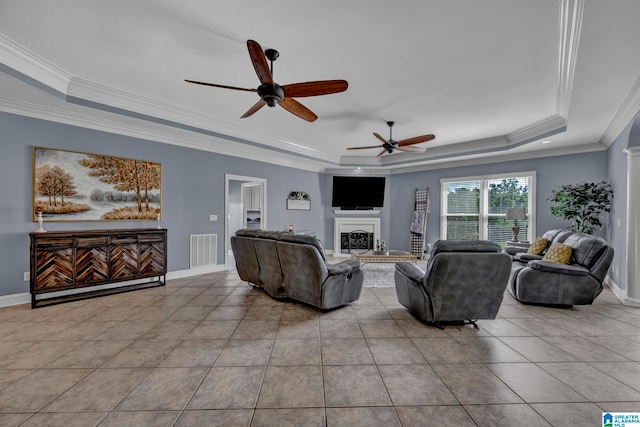 living room with ornamental molding, ceiling fan, light tile flooring, and a tray ceiling