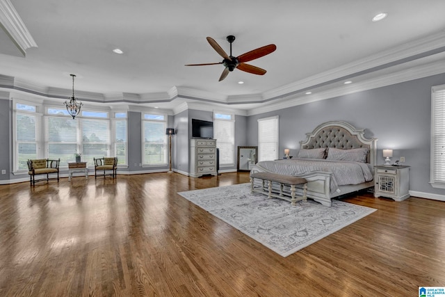 bedroom featuring ceiling fan with notable chandelier, a tray ceiling, hardwood / wood-style flooring, and ornamental molding