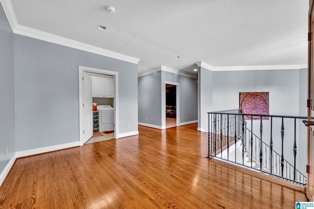 empty room featuring washer / clothes dryer, light wood-type flooring, and ornamental molding