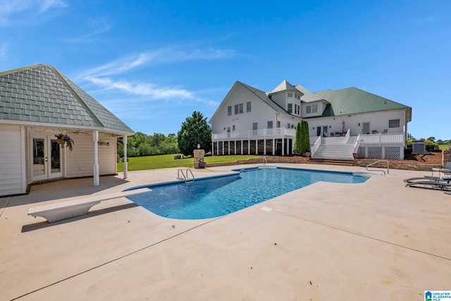 view of pool featuring a patio area, a diving board, and french doors