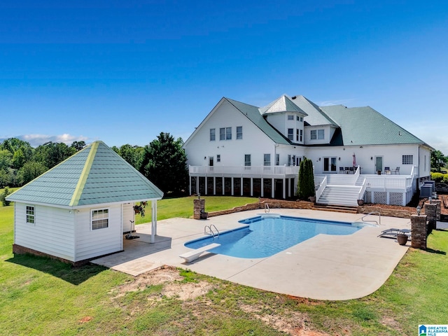 view of pool with a patio, a yard, an outdoor structure, a wooden deck, and a diving board