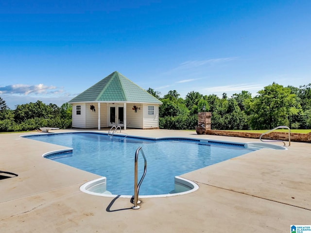 view of swimming pool featuring a patio, a diving board, and an outdoor structure