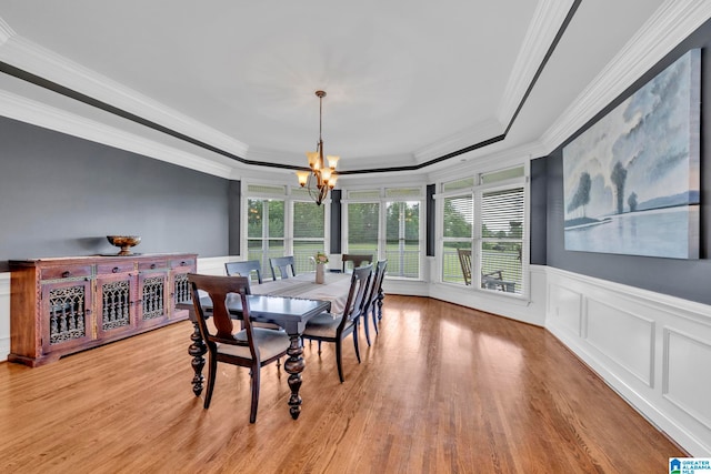 dining area featuring ornamental molding, a notable chandelier, light hardwood / wood-style flooring, and a raised ceiling