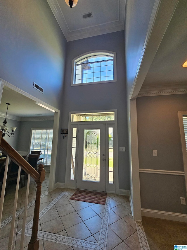 entrance foyer with a healthy amount of sunlight, tile floors, a chandelier, and crown molding