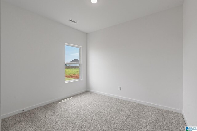 empty room with carpet floors, visible vents, and baseboards