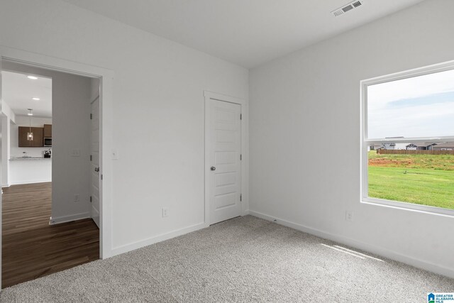 unfurnished bedroom featuring dark colored carpet, visible vents, and baseboards