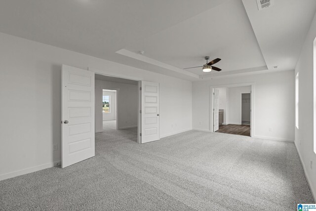 unfurnished bedroom with carpet, a raised ceiling, visible vents, and baseboards