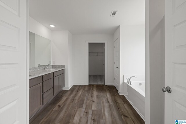 bathroom featuring a garden tub, visible vents, vanity, wood finished floors, and baseboards