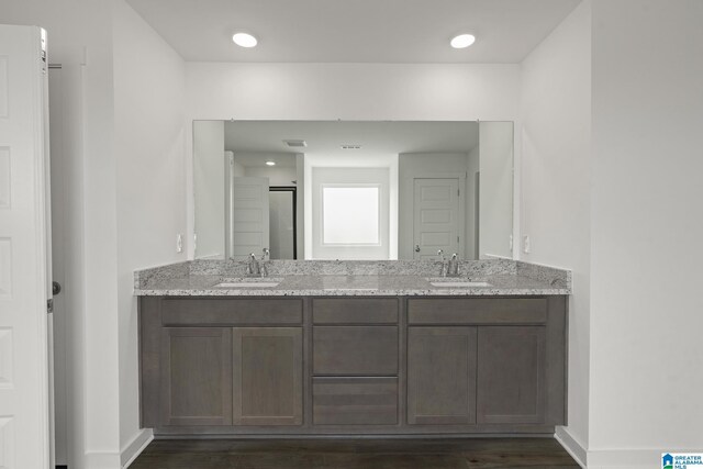 bathroom featuring a sink, a shower stall, baseboards, and wood finished floors