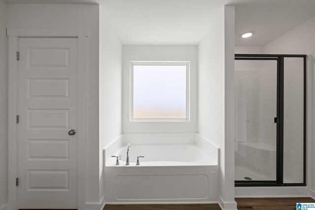 bathroom with a stall shower, wood finished floors, and a bath