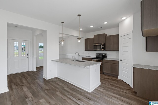 kitchen with decorative light fixtures, appliances with stainless steel finishes, a sink, light stone countertops, and a peninsula