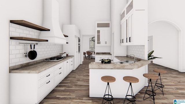 kitchen featuring a kitchen bar, dark hardwood / wood-style flooring, stainless steel gas cooktop, sink, and white cabinetry