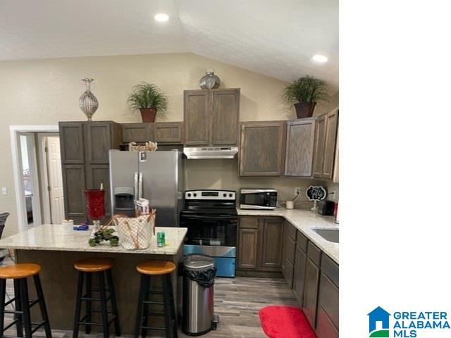 kitchen featuring a center island, appliances with stainless steel finishes, hardwood / wood-style floors, and vaulted ceiling