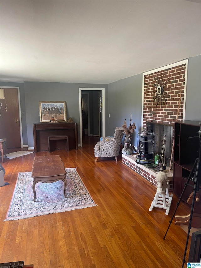 unfurnished living room featuring brick wall, wood-type flooring, and a brick fireplace