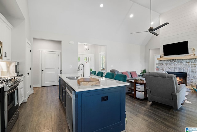 kitchen featuring a brick fireplace, ceiling fan, dark wood-type flooring, white cabinetry, and sink