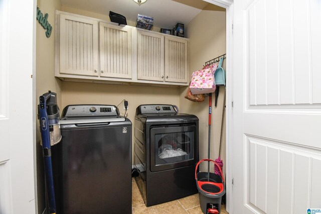 clothes washing area with light tile flooring, washer and dryer, and cabinets