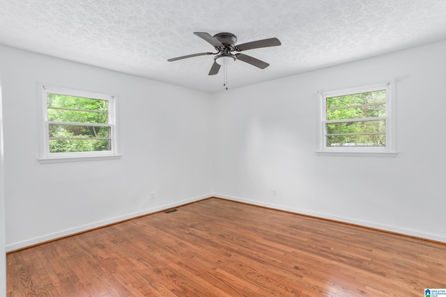 empty room featuring ceiling fan, a healthy amount of sunlight, and hardwood / wood-style flooring