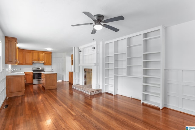 kitchen with a brick fireplace, ceiling fan, dark hardwood / wood-style floors, sink, and stainless steel range with electric stovetop