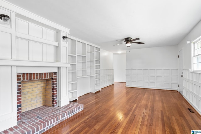 unfurnished living room featuring wood-type flooring, ceiling fan, and a fireplace