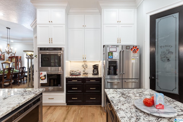 kitchen with light wood-type flooring, white cabinetry, a chandelier, and stainless steel appliances