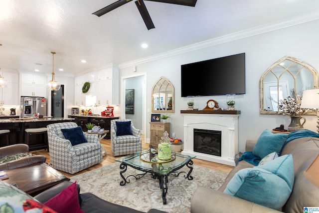 living room featuring ceiling fan, light hardwood / wood-style floors, and crown molding