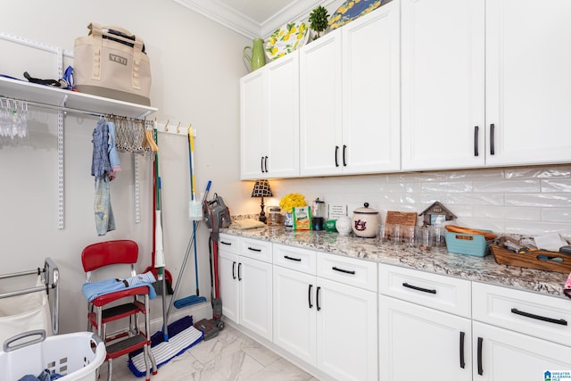 kitchen featuring crown molding, light stone countertops, decorative backsplash, and white cabinetry