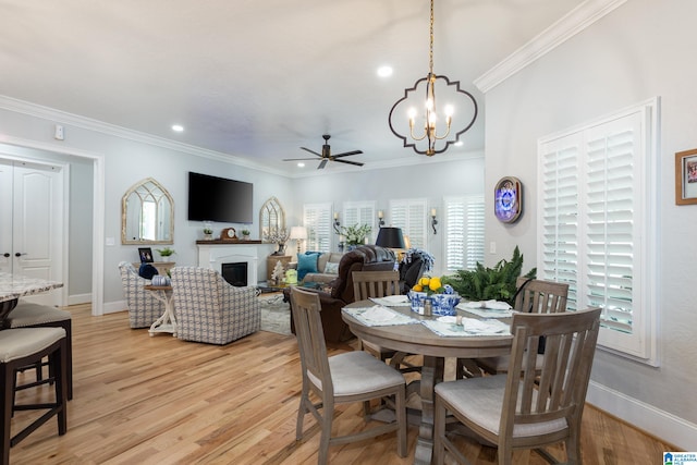 dining area featuring ceiling fan with notable chandelier, ornamental molding, and light hardwood / wood-style flooring