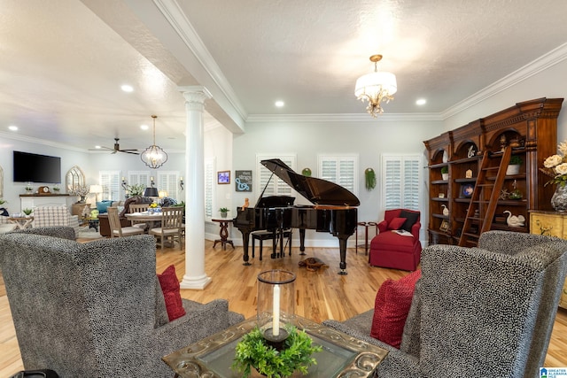 sitting room with light hardwood / wood-style flooring, ornamental molding, ceiling fan with notable chandelier, and ornate columns