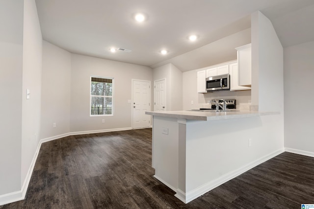 kitchen featuring white cabinetry, sink, dark hardwood / wood-style flooring, kitchen peninsula, and a kitchen bar