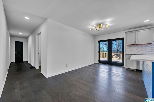 unfurnished living room featuring dark hardwood / wood-style floors and an inviting chandelier