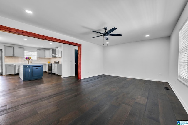 unfurnished living room with dark hardwood / wood-style flooring and ceiling fan