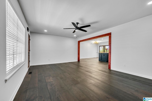 spare room with a healthy amount of sunlight, ceiling fan, and dark hardwood / wood-style floors