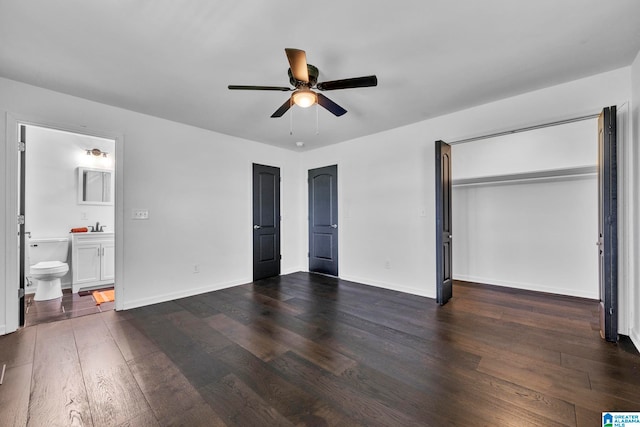 unfurnished bedroom featuring sink, ceiling fan, a closet, dark wood-type flooring, and ensuite bathroom