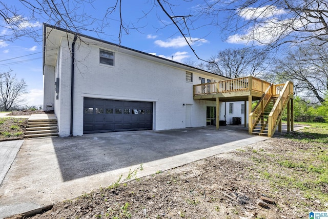 rear view of house with brick siding, a deck, a garage, driveway, and stairs