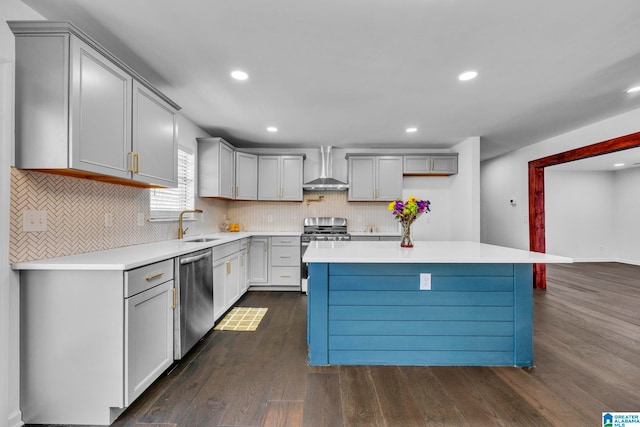 kitchen with wall chimney range hood, a center island, stainless steel appliances, and dark hardwood / wood-style floors